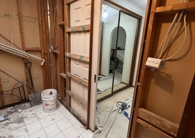 Bathroom stripped to the frame with old floor tiles partly removed and a skylight above