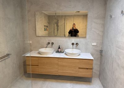 Double vanity with two vessel basins, timber drawers and a long mirror cabinet