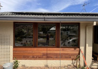 Horizontal timber cladding under timber-framed windows on a rendered house