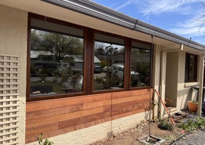 Timber-framed windows and horizontal timber cladding along a rendered wall