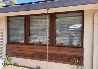 Three timber-framed windows above new timber cladding, viewed straight on